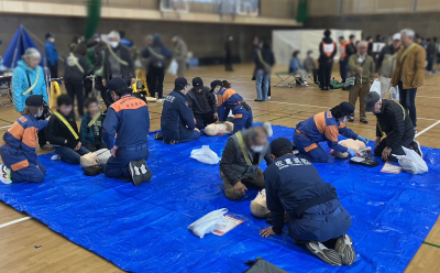 総合防災訓練にて、参加者に心肺蘇生法やAEDの使用方法を教える女性消防班の様子。