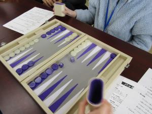 バックギャモンの道具を挟み、向かい合う子ども